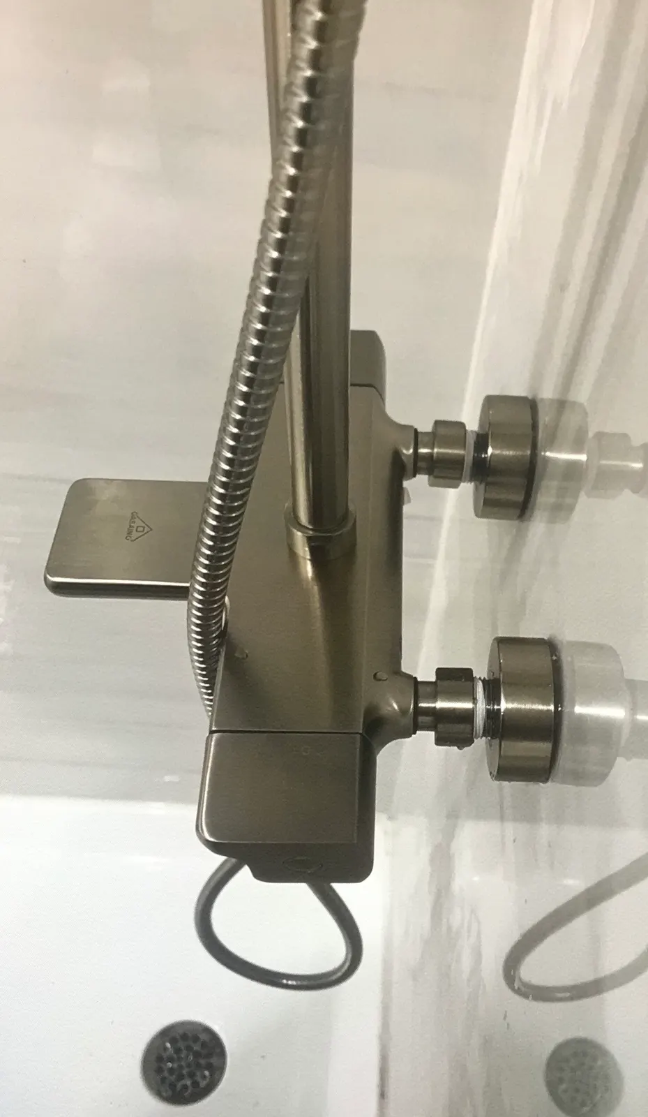 Close-up of a thermostatic shower bar in a dark brushed-metal finish, connected at the wall.