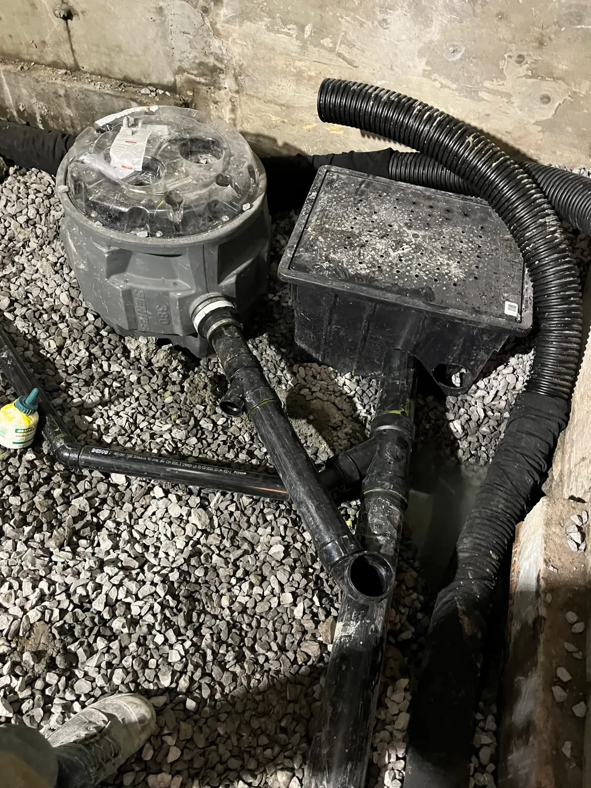Sump basin and catch box connected to the weeping tile and ABS drain, set in gravel before the slab.