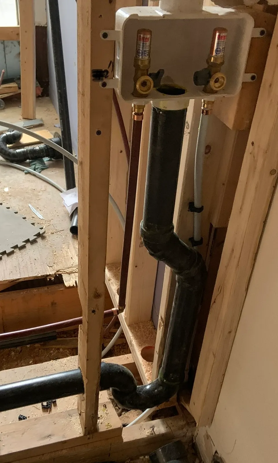 Washing-machine outlet box with valves and water-hammer arrestors, and an ABS drain, in an open stud wall.