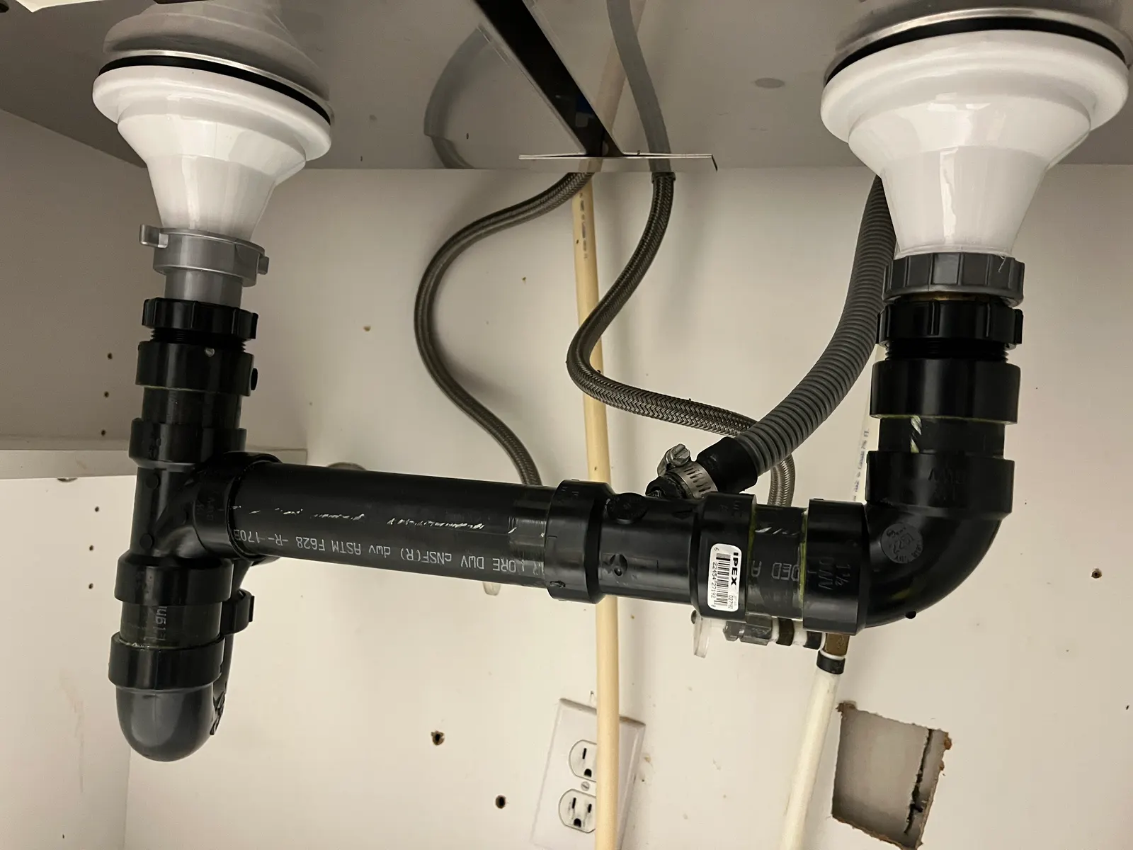 ABS drain joining both bowls of a kitchen sink, with the dishwasher hose connected.