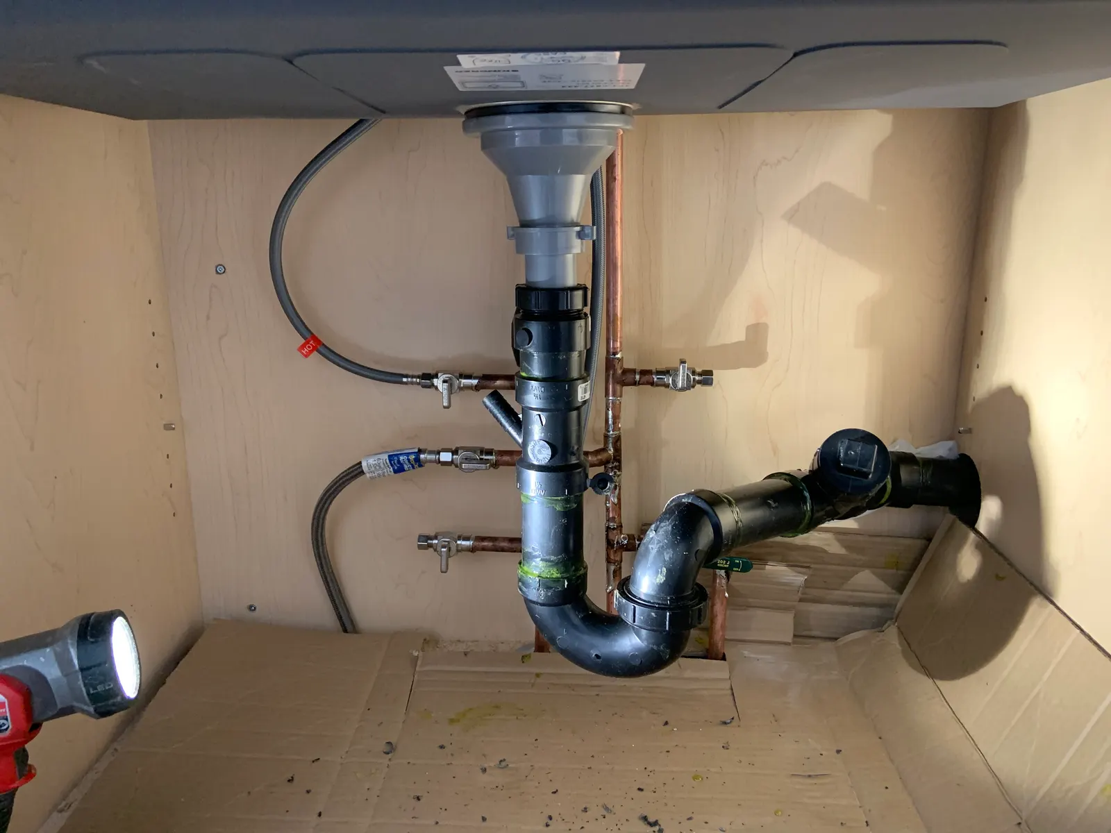 New ABS drain and trap under a kitchen sink, with copper supply lines fitted with shut-off valves.