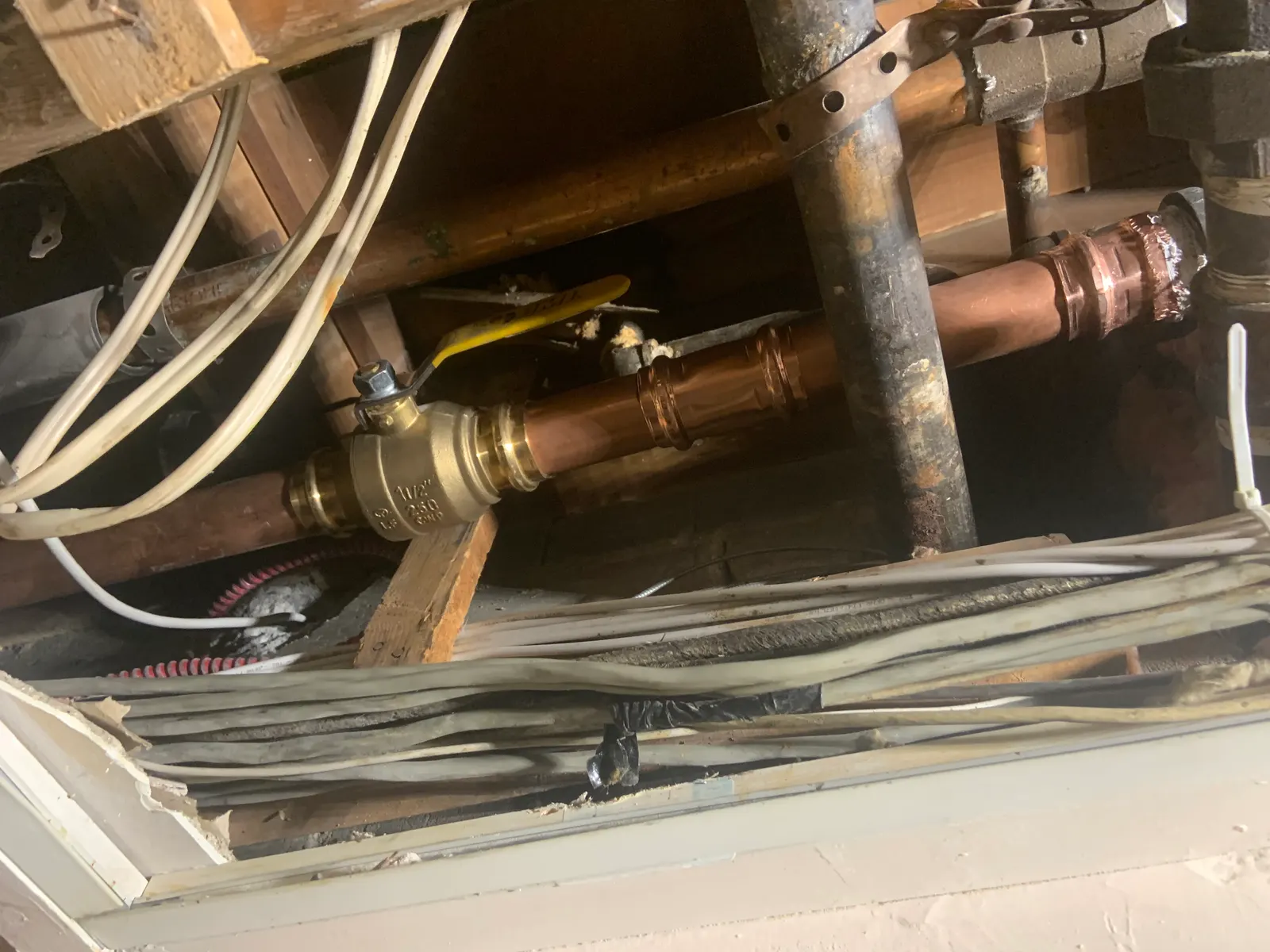 Copper pipe in a ceiling with a new brass ball valve and new fittings.