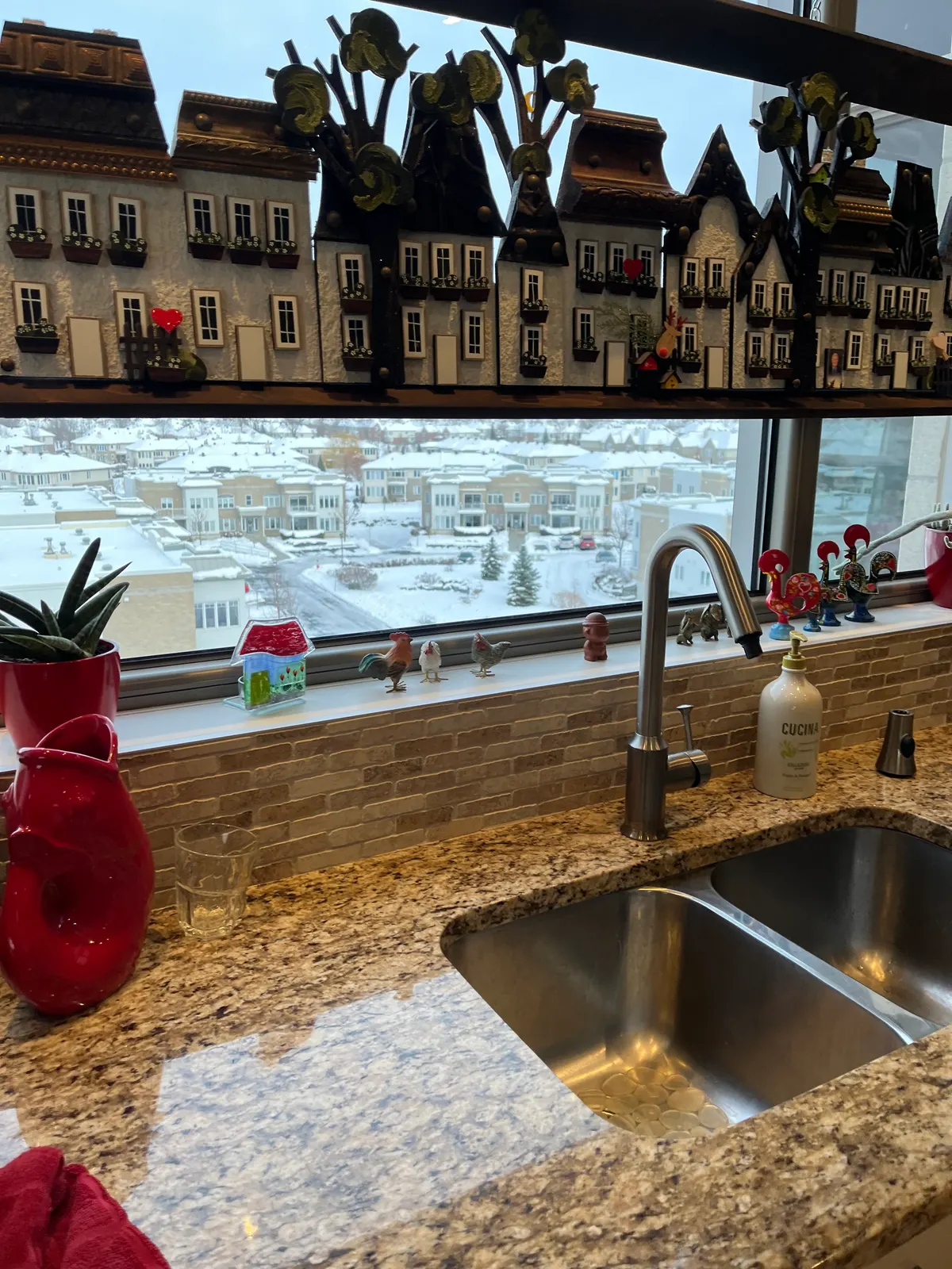 High-arc kitchen faucet over a double stainless-steel sink undermounted in a granite counter.