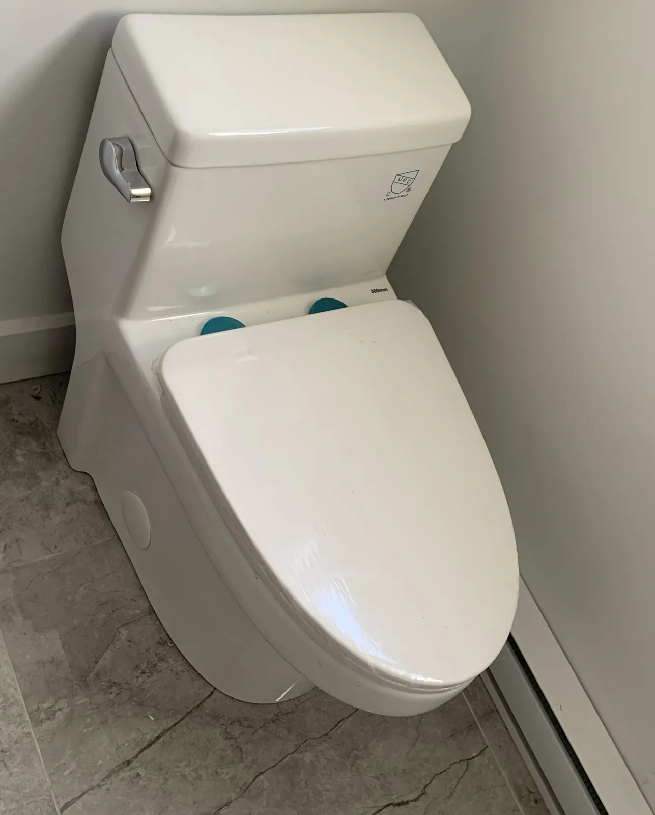 New elongated one-piece toilet installed on a grey tile floor.